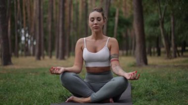 Huzurlu ve sakin bir ormanda, bir kadın huzur içinde meditasyon yapar, yoga pratiğiyle farkındalığı ve dengeyi somutlaştırır.