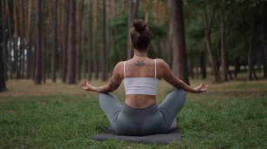 Bir kadın huzurlu bir ormanda huzur içinde meditasyon yapıyor. Doğanın ve farkındalığın güzelliğini tamamen kucaklıyor.