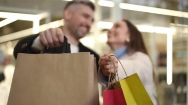 Neşeli bir çift alışverişlerle dolu alışveriş çantalarını tutarken parlak bir şekilde gülümsüyor. Kara Cuma satışlarının ve indirimlerin heyecanını kutlarken, mutlulukları,