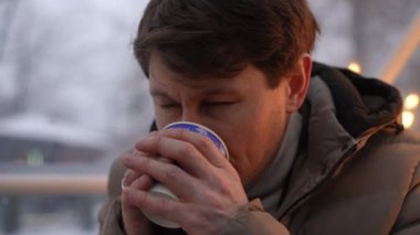 Genç bir adam sakin bir kış manzarasına derin bir şekilde yansıyor. Yumuşak kar taneleri sakin bir atmosfer yaratıyor.