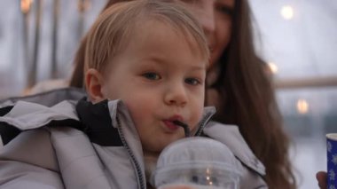 Neşeli bir çocuk, kışın ılık ve samimi atmosferiyle çevrili, sütle dolu bir fincan tutar.