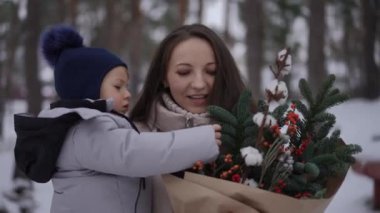 Sevgi dolu bir anne ve çocuğunun, sevgi dolu bir kış sahnesi. Yeşilliğin tadını çıkarıyorlar.