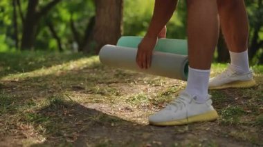 Bir insan yoga minderlerini güzel, sakin bir açık havada tutuyor, sağlığını ve farkındalık uygulamalarını teşvik ediyor.