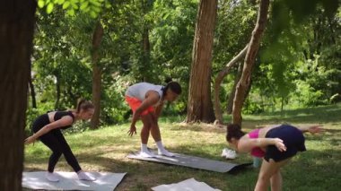 Canlı bir açık hava yoga seansı gerçekleşir, katılımcılar sevinçle kollarını gökyüzüne doğru uzatırlar.