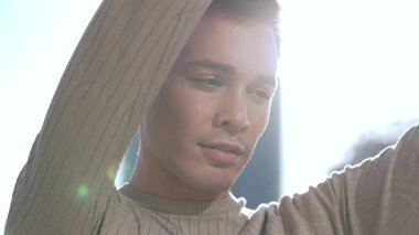 Modayı takip eden genç bir adam, kendine güvenerek dışarıda poz verir, modern stil yayar ve cazibeyle kendine güvenir.