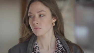 Moda kıyafetli uzun saçlı genç bir kadın enerjik ve enerjik bir şehir ortamında düşünceli bir şekilde bakıyor.