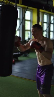 Kendini işine adamış ve odaklanmış bir boksör, güçlü bir spor salonunda muazzam bir yetenek sergileyen ağır bir çantayla idman yapar.