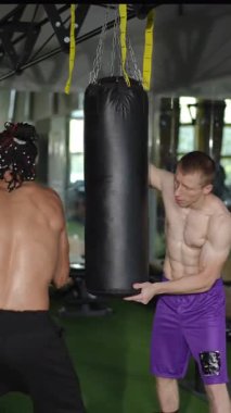 İki yetenekli sporcu, kum torbasını kullanarak dinamik ve yoğun bir boks antrenmanı yapıyorlar.