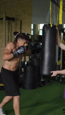 Bir boksör yoğun bir antrenmanda ağır bir torbaya vuruyor. Yetenek ve özveri gösterisi yapıyor..