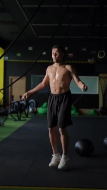Formda bir birey modern bir spor salonunda ip atlama egzersizleri yapıyor, atletizm ve fitness için kendini adamışlık sergiliyor.