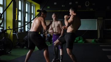 Modern bir spor salonunda, üç yetenekli boksör yoğun egzersizler sırasında tekniklerini sergiliyorlar.