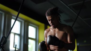 Kendini adamış ve odaklanmış bir boksör, spor salonunda yoğun bir şekilde antrenman yapıyor, muazzam bir güç ve bağlılık gösteriyor.