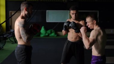 Modern bir spor salonunda üç sporcu, adanmışlık ve tekniği sergileyerek boks eğitimine odaklanır..