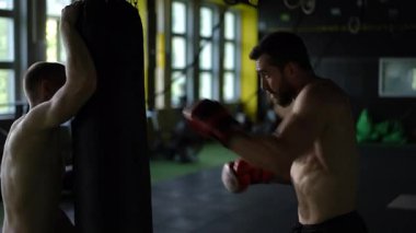 Ağır kum torbaları ve eldivenleriyle yoğun antrenman yapan kendini adamış sporcuların dinamik anlarına tanık olun.