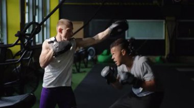 Kendini spora adamış iki sporcu spor salonunda ağırlıklarla yoğun bir boks antrenmanına giriyorlar.