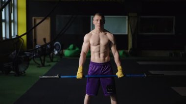 Güçlü ve kaslı bir birey modern bir spor salonunda ağırlık kaldırma egzersizine hazırlanıyor.