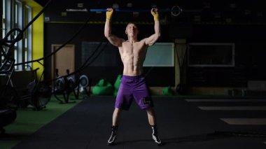 Sporcunun biri canlı bir spor salonunda halter egzersizi yapıyor. Forma ve sağlığa olan bağlılıklarını gösteriyor.