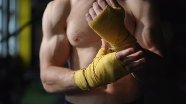 İnanılmaz derecede odaklanmış ve kendini işine adamış bir sporcu yoğun bir boks antrenmanına hazırlanmak için ellerini dikkatlice sarıyor.