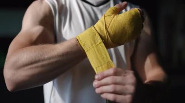 Kendini işine adamış ve odaklanmış bir sporcu yoğun ve zorlu bir boks antrenmanına hazırlanmak için ellerini dikkatlice sarıyor.