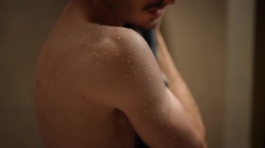 Duştan sonra nemli bir tenin yakın plan görüntüsü, yumuşak bir havluya sarılı ve sıcak, nazik bir ışıkla aydınlatılıyor.