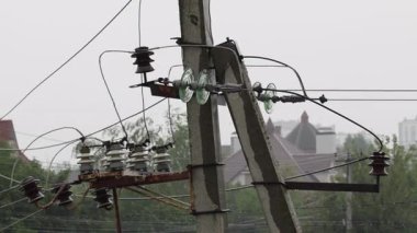 Bulutlu gökyüzünün altında hareketli bir kentsel alanda elektrik direklerinin ve karmaşık elektrik hatlarının çarpıcı görüntüsü