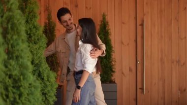 Bir çift, verimli yeşilliklerle çevrili, güzel tasarlanmış ahşap bir alanda neşeli bir anın tadını çıkarıyor.