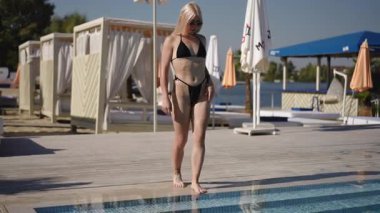 Havuz kenarında güneşli bir günün tadını çıkaran bir kadın şık ve şık bir mayo, derin rahatlama için ideal.