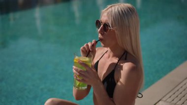 Canlı yeşil bir içkinin tadını çıkarıyorum. Havuz kenarında, güneşin altında, neşeyle dinlenirken.