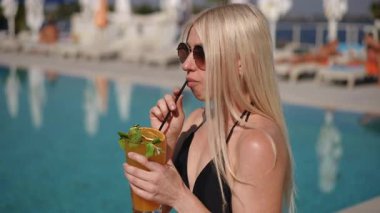 Güneşli bir günde, havuz başında eğlenirken rahatlamak ve hava almak için mükemmel bir tropikal kokteyl yudumluyoruz.