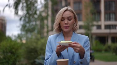 Zarif bir kadın açık havada lezzetli atıştırmalıkların tadını çıkarıyor, canlı yeşillikler arasında zarafet yayıyor.