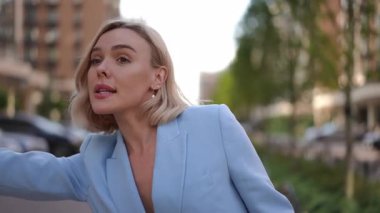 Açık mavi takım elbiseli genç bir kadın işlek bir caddede geziniyor..