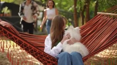 Neşeli bir arkadaş grubu, rahat bir hamakta rahat bir gün geçirir tüylü köpekleri ile.