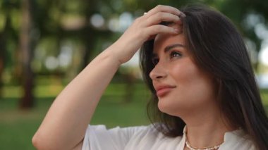 Huzurlu ve büyüleyici bir portre güzel bir şekilde sergilenen dalgalı saçlı bir kadın, yemyeşil bir zemin üzerine kurulmuş