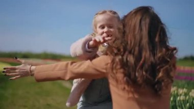 Canlı bir lale bahçesinde sevgi dolu bir ebeveyn ve çocukları arasında samimi bir kucaklaşma gerçekleşir.