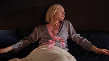 Huzurlu bir sabah sahnesi. Lüks ipek bornozlu bir kadın. Esniyor ve sükunetinin tadını çıkarıyor.