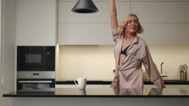 Parlak ve neşeli bir sabah sahnesinde şık bir mutfak ortamında gününü güzelce geçiren bir kadın resmediliyor.