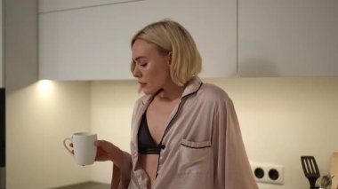 Bir kadın, sakin ve sakin bir sabah anının tadını çıkarır. Kahvesiyle, şık bir mutfak ortamında tamamen kucaklayıcı bir rahatlıkla.