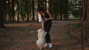 Neşeli bir kadın huzurlu bir orman zemininde tüylü ve sevimli köpeğiyle neşeli bir anın tadını çıkarıyor.