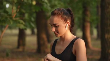 Ağır çekim. Aktif bir kadın doğada koşuyor, susuzluğunun tadını çıkarıyor ve kulaklıklarıyla müzik dinlemekten zevk alıyor.