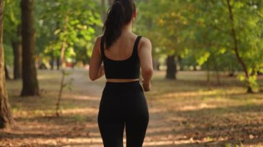 Ağır çekim. Bir kadın sakin, huzurlu bir parkta koşar. Hem doğayı hem de spor hayatını tamamen kucaklar.