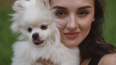 Genç bir kadın, sevimli pomeranyasını açık havada kucaklıyor ve paylaştıkları özel bağı vurguluyor.