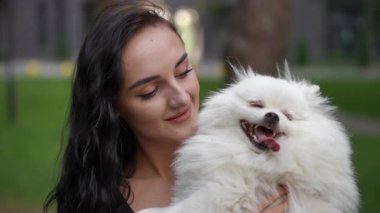 Neşeli bir kadın, canlı, güzel yeşil bir ortamda tüylü Pomeranian 'ıyla keyifli bir anı paylaşıyor.