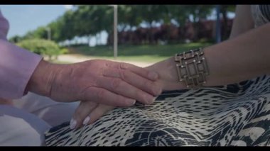 Madrid 'li yaşlı bir adamın elini nazikçe elbisesinin üzerine koyması. Sakin bir park karşılaşması sırasında sıcaklığını, bağlantısını ve duygusal yakınlığını ifade etmesi..