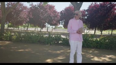 Madrid 'den gelen güneş gözlüklü ve pembe tişörtlü neşeli yaşlı adam sırt çantası taşıyan gülümseyen bir kadınla sohbet ederken kitap okuyor, dışarıda arkadaşça ve entellektüel bir anın tadını çıkarıyor..