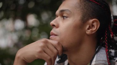 Düşüncelere dalmış genç bir adam, uzaklığa bakıyor, benzersiz bir yansıma ve içgözlem anı yakalıyor.