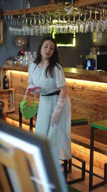 Modaya uygun bir kadın şık bir kafede zarif bir şekilde poz verir. Benzersiz ve kendine özgü tarzını güzel bir şekilde sergiler.