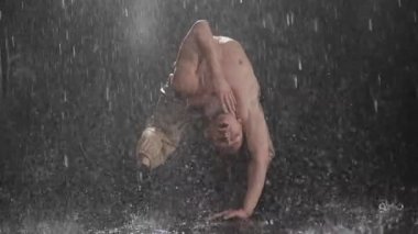 Düşen su damlacıkları arasında etkileyici hareketler sergileyen büyüleyici bir dans gösterisi.