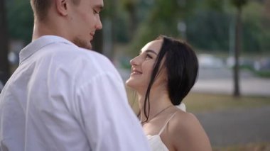 Gelin ve damat parkta bir arabanın yanında nazikçe dans eder, el ele tutuşur ve birbirlerine sevgiyle bakarlar. Romantizmin hassas anı doğal bir doğa ortamında yakalanır..