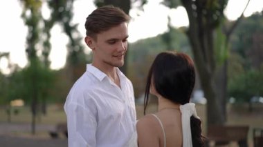 Damat gelini kucaklar, açık havada yavaşça dans ederken, hassas ve samimi bir anı paylaşır. Gözleri, aşk ve bağlantıyı yansıtıyor. Romantizm ve kutlama sahnesi yaratıyor..