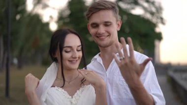 Neşeli bir çift düğünlerini kutluyor, güzel yüzükler ve geniş gülümsemeli derin aşklar sergiliyorlar.